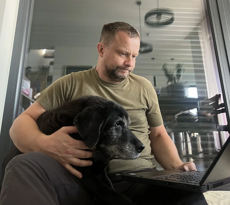 Sławomir Pięta pracuje przy laptopie, na kolanach ma starszego psa